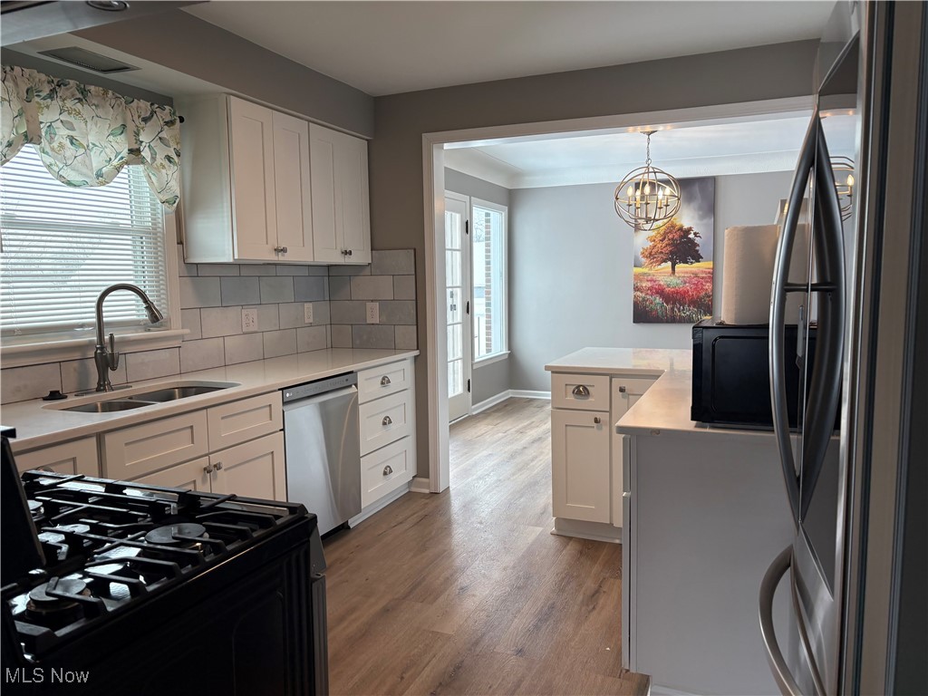 7817 Dalebrook Road Independence, OH 44131 - Photo 12 of 28 Kitchen featuring pendant lighting, sink, appliances with stainless steel finishes, white cabinets, and decorative backsplash