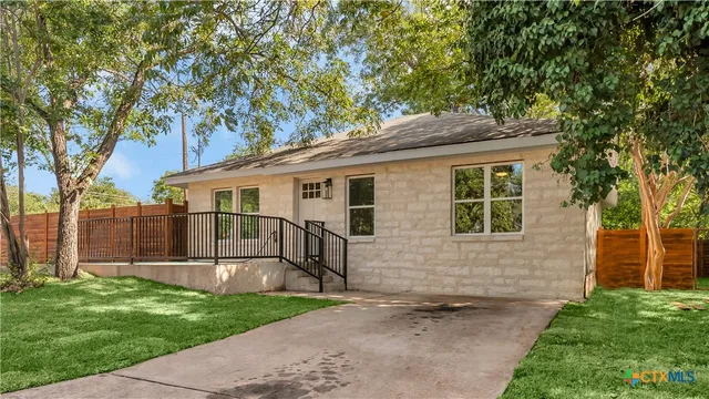 a white house that has tree in front of it
