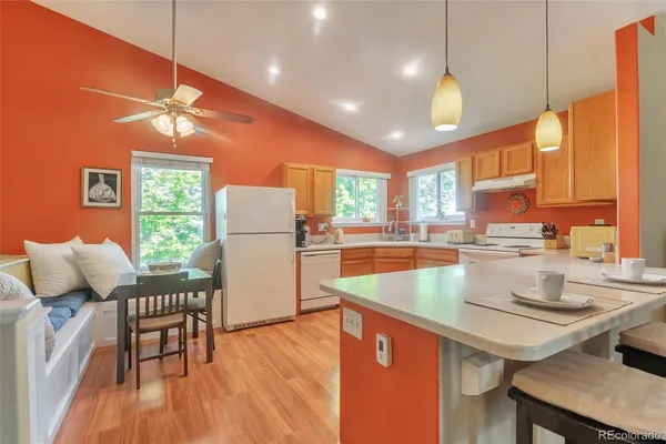 a kitchen with stainless steel appliances granite countertop a stove a refrigerator a kitchen island a dining table and chairs with wooden floor