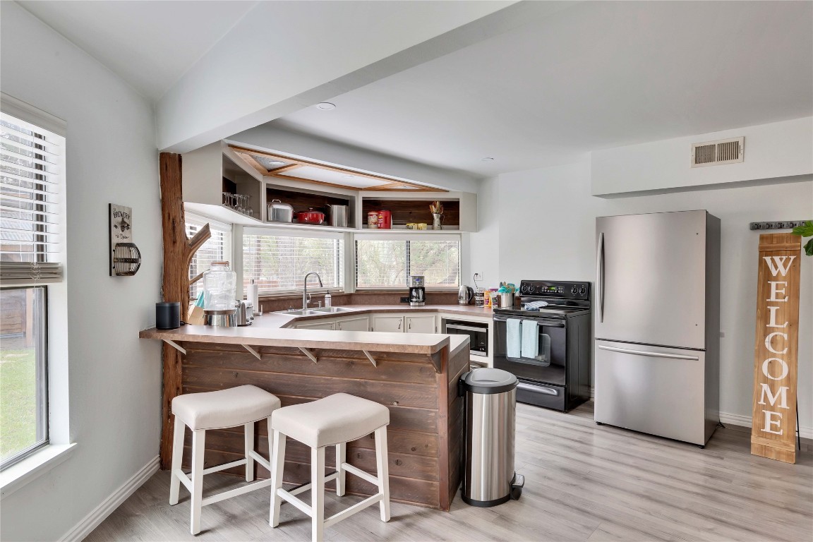 16108 Aqua Azul Path Austin, TX 78734 - Photo 13 of 40 a kitchen with a refrigerator a stove a sink and a dining table with wooden floor