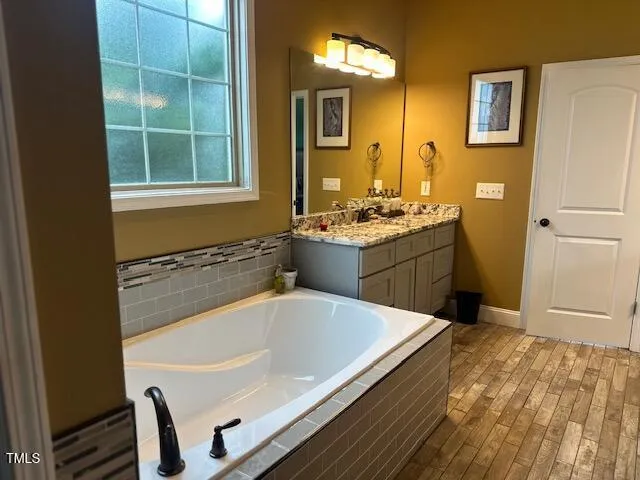 a bathroom with a tub sink and mirror