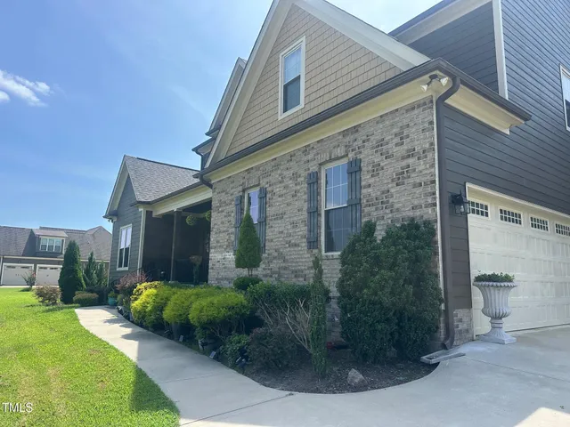 a view of a brick house with a yard potted plants and a table and chairs