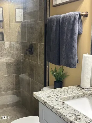 a bathroom with a granite countertop sink a toilet and shower