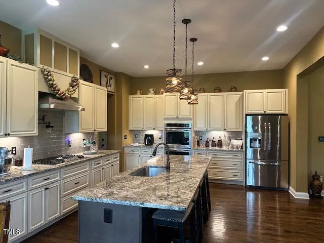 a kitchen with stainless steel appliances kitchen island granite countertop a sink refrigerator and cabinets