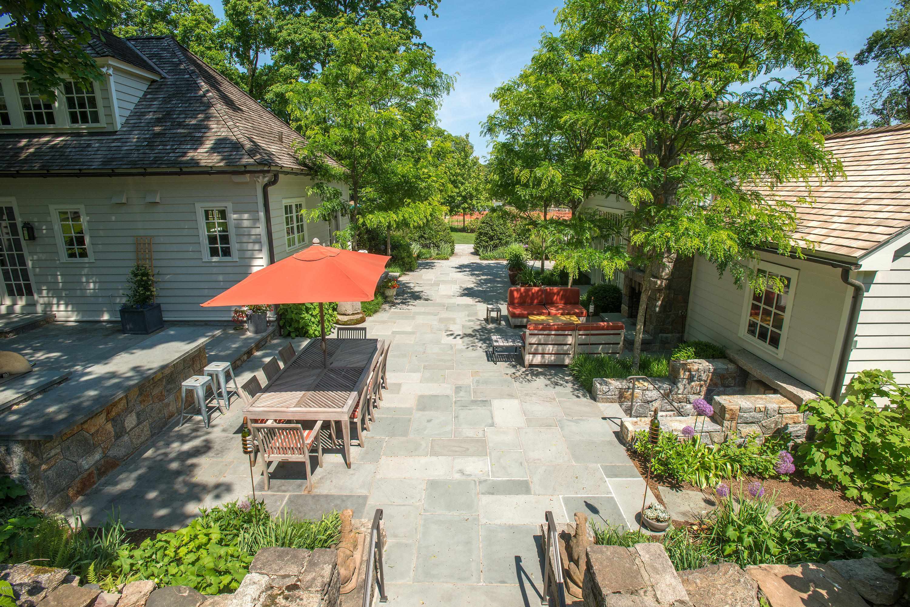 8 Mountain Wood Drive Greenwich, CT 06830 - Photo 11 of 22 a backyard of a house with table and chairs under an umbrella