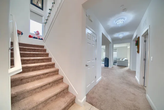 a view of a hallway with stairs and a livingroom view