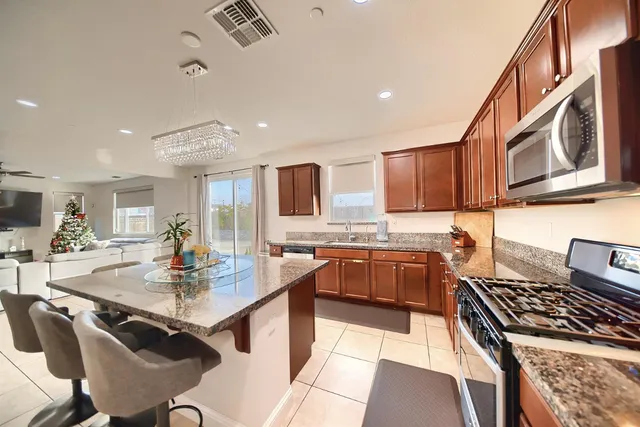 a kitchen with stainless steel appliances granite countertop a stove a sink dishwasher and cabinets with wooden floor