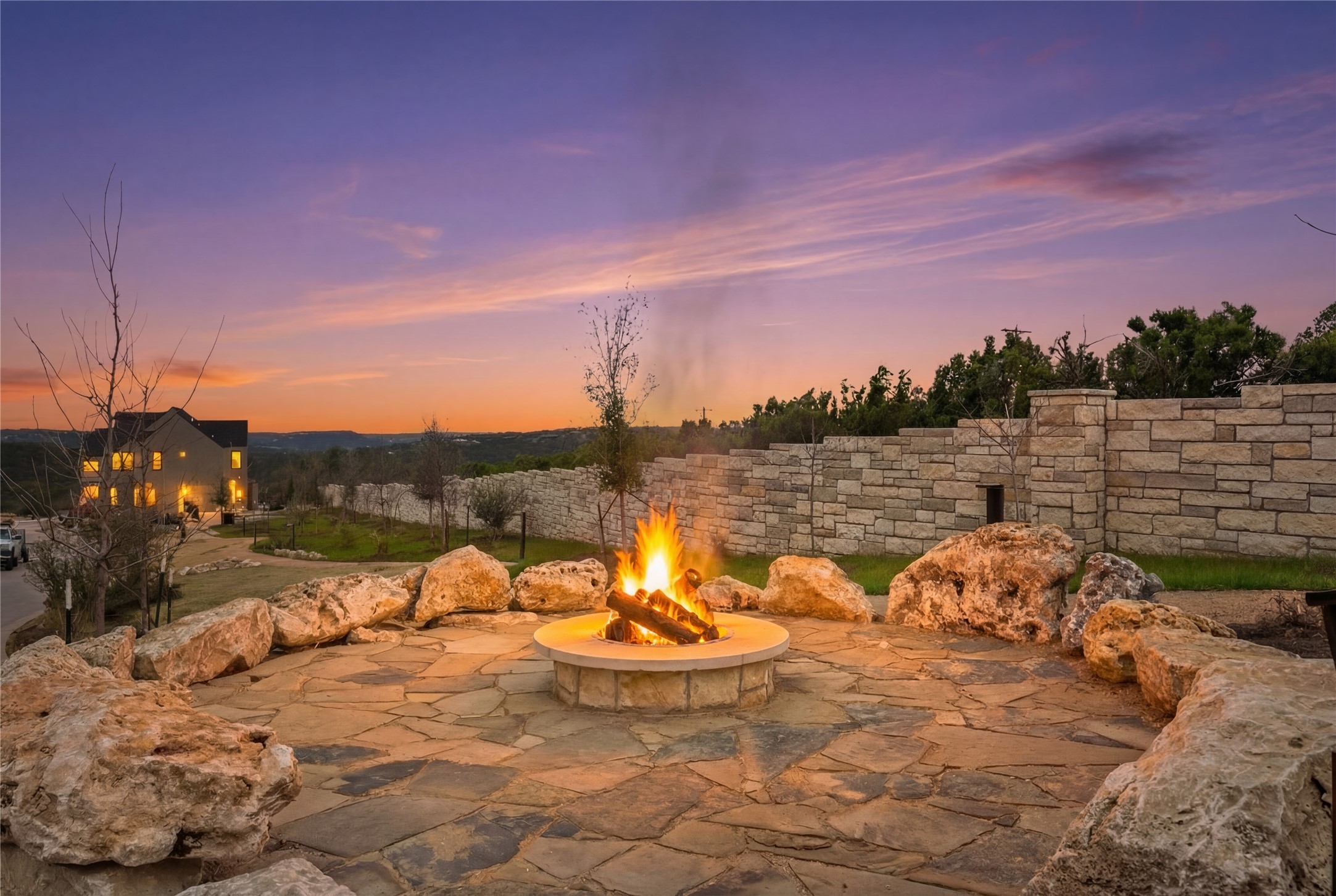 9803 Ribelin Ranch Court, Unit 21 Austin, TX 78750 - Photo 19 of 20 Outdoor fire pit area featuring a stone patio, a circular fire pit with a fire, and surrounding natural rock seating
