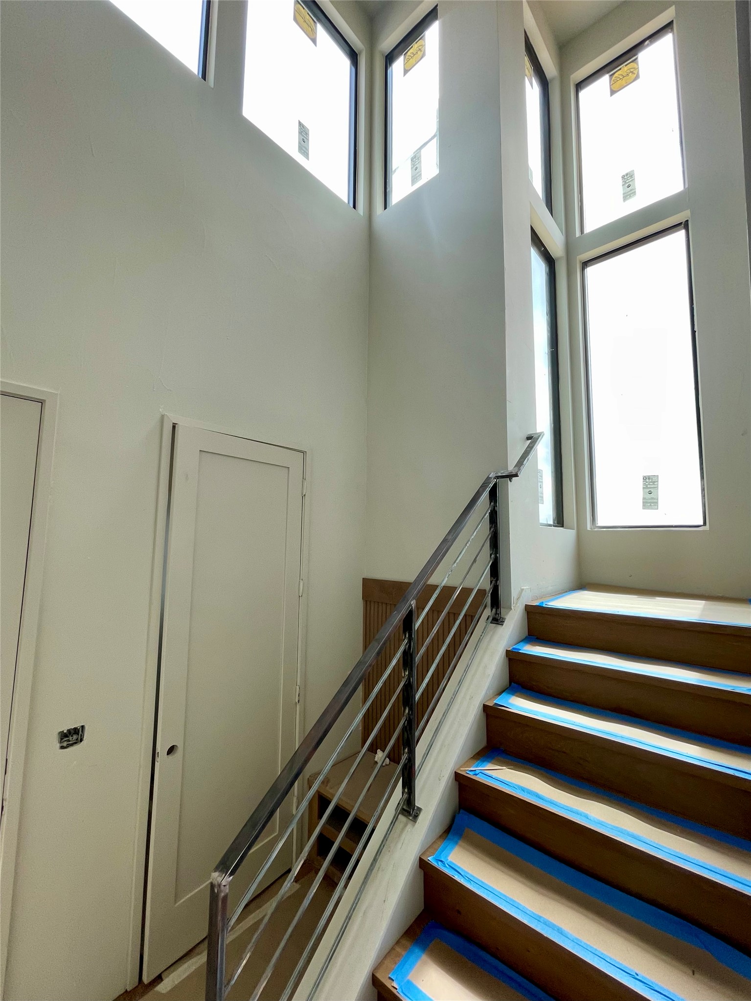 9803 Ribelin Ranch Court, Unit 21 Austin, TX 78750 - Photo 8 of 20 Staircase featuring dark wood steps, a modern metal railing, and high windows providing natural light