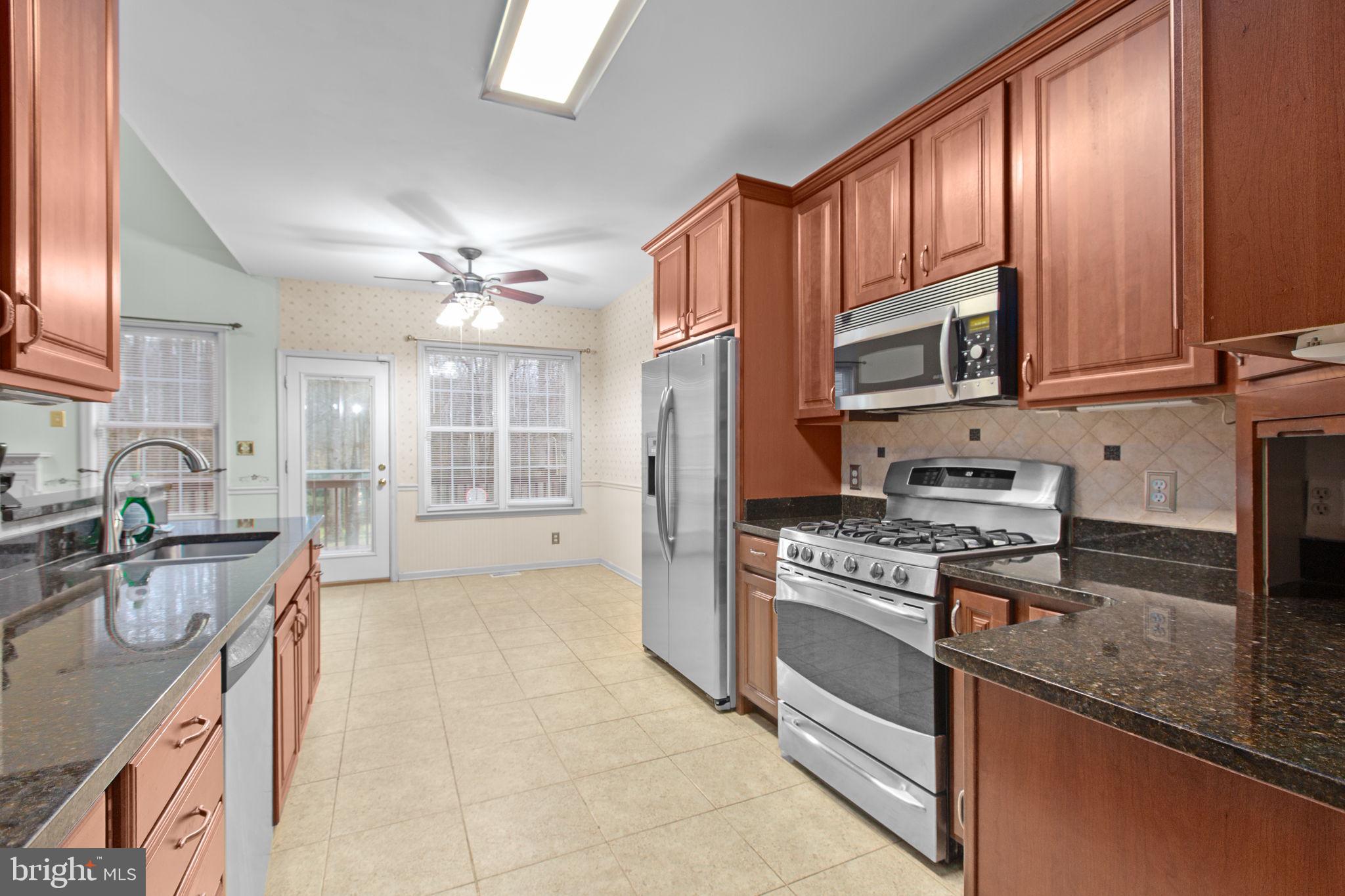 10721 Colbys Lane King George, VA 22485 - Photo 10 of 50 a kitchen with stainless steel appliances granite countertop a stove top oven a sink dishwasher a refrigerator and cabinets with wooden floor