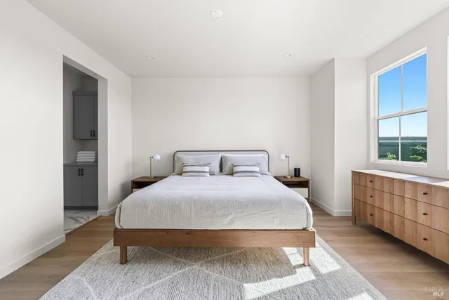 a bedroom with a bed a window with wooden floor