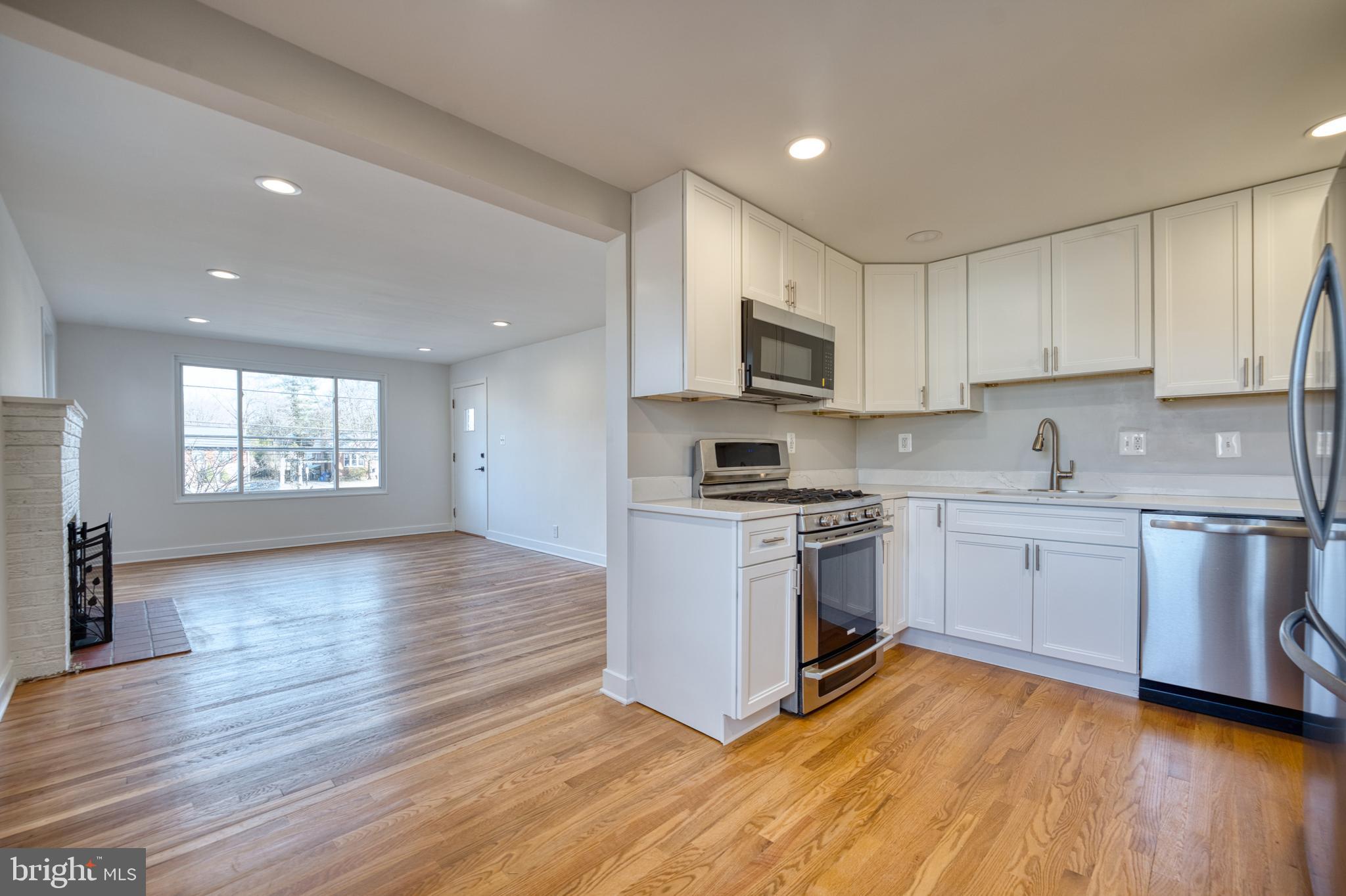 12214 Connecticut Avenue Silver Spring, MD 20902 - Photo 5 of 18 a kitchen with granite countertop wooden floors a stove a sink and a window