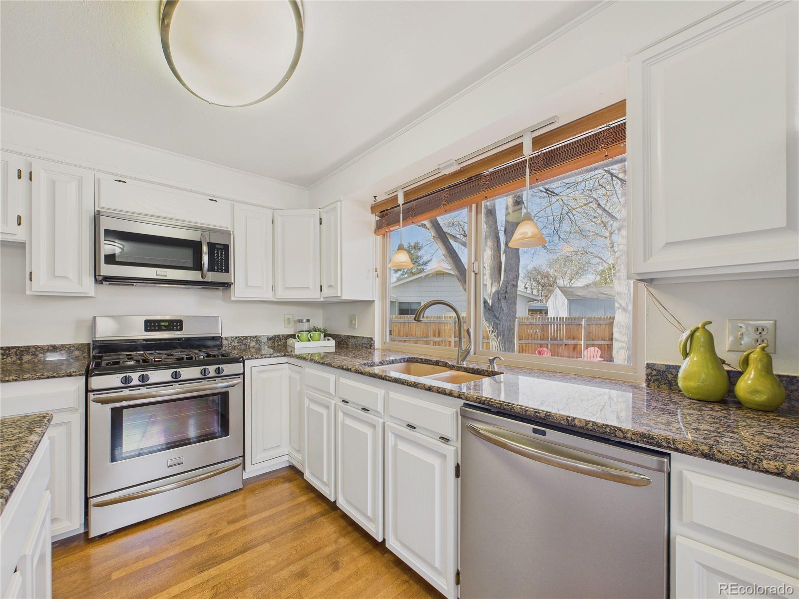 8373 Zephyr Street Arvada, CO 80005 - Photo 18 of 31 a kitchen with stainless steel appliances granite countertop a sink a stove and a microwave