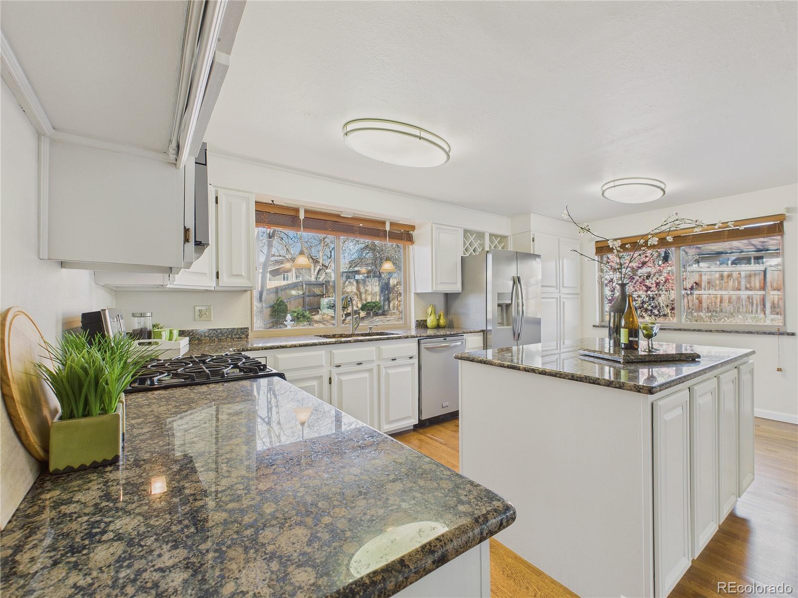 8373 Zephyr Street Arvada, CO 80005 - Photo 25 of 31 a kitchen with granite countertop white cabinets and white appliances