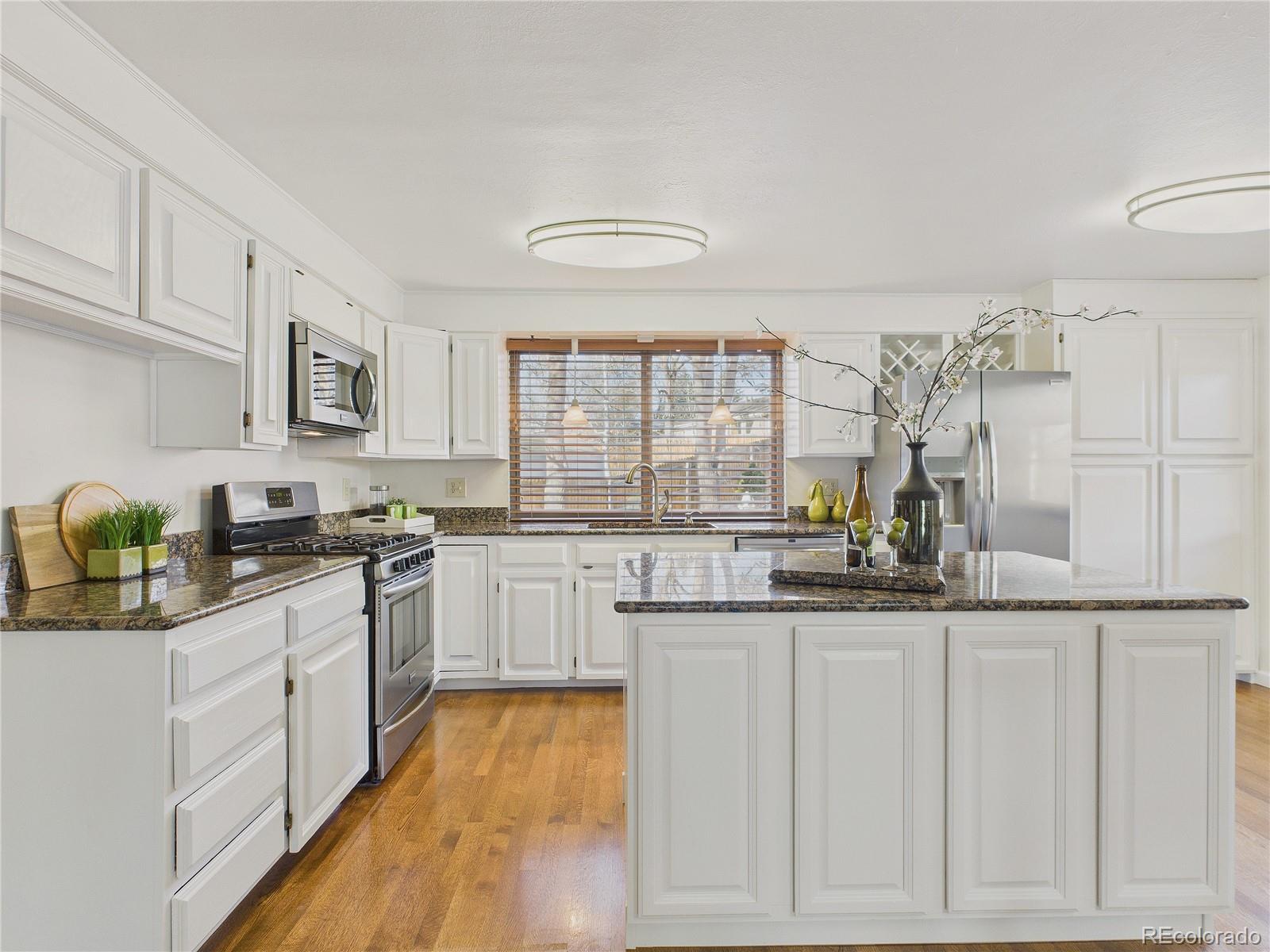 8373 Zephyr Street Arvada, CO 80005 - Photo 6 of 31 a kitchen with granite countertop white cabinets and white appliances