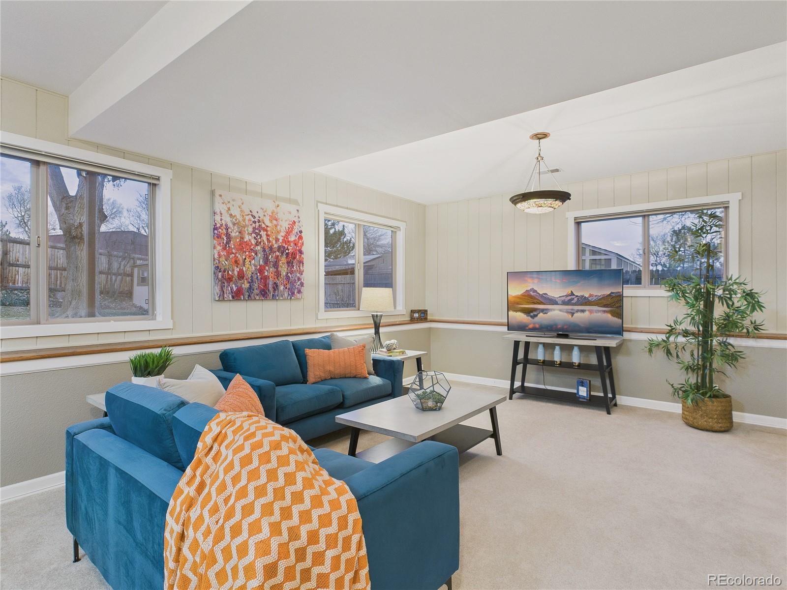 8373 Zephyr Street Arvada, CO 80005 - Photo 8 of 31 a living room with furniture and paintings on the wall