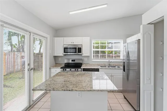 a kitchen with stainless steel appliances granite countertop a refrigerator sink and stove