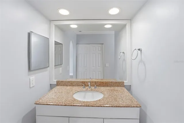 a bathroom with a granite countertop sink a mirror and shower