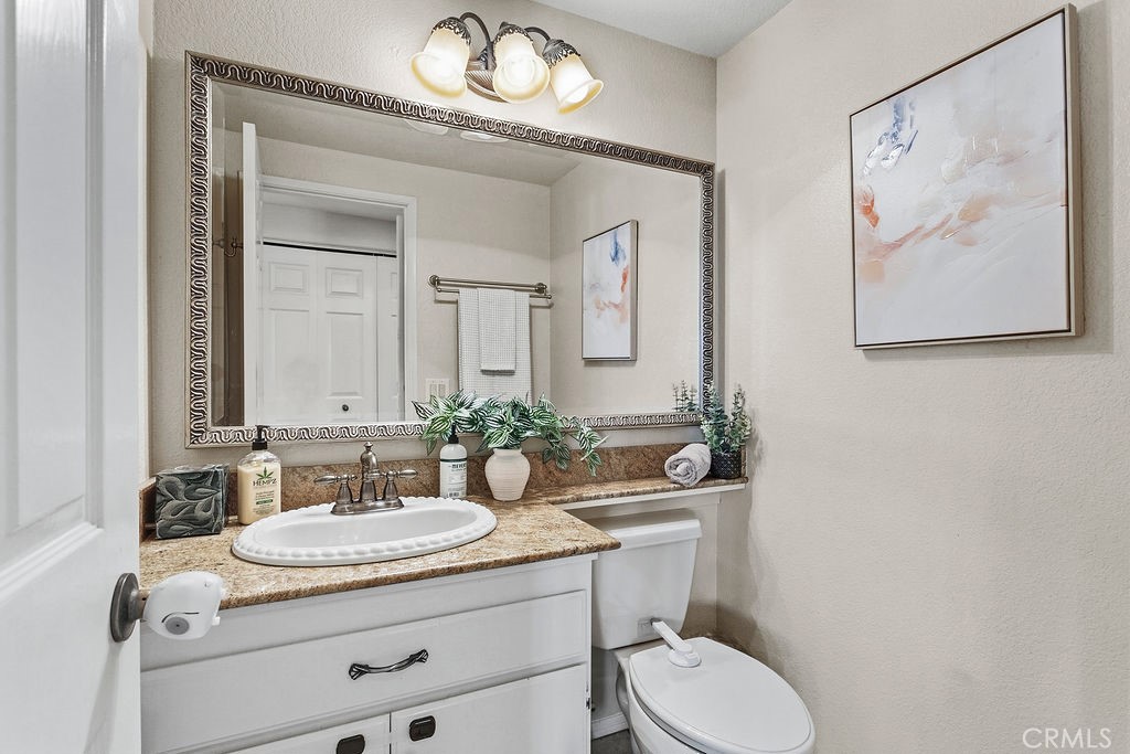 22720 Springmist Drive Moreno Valley, CA 92557 - Photo 23 of 40 a bathroom with a granite countertop toilet a sink and a mirror