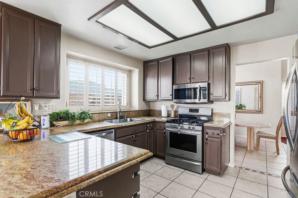 22720 Springmist Drive Moreno Valley, CA 92557 - Photo 6 of 40 a kitchen with stainless steel appliances granite countertop a stove a sink and a microwave