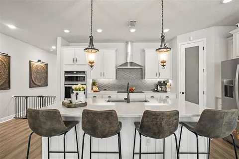 a kitchen with stainless steel appliances kitchen island granite countertop a dining table chairs and a refrigerator