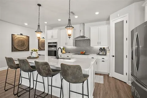 a kitchen with stainless steel appliances kitchen island granite countertop a refrigerator a stove a microwave oven a sink with island chairs and wooden floor