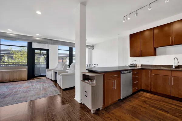 a kitchen with stainless steel appliances granite countertop wooden cabinets a sink a stove a dining table and chairs
