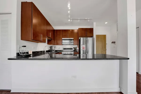 a kitchen with stainless steel appliances granite countertop a sink refrigerator and microwave