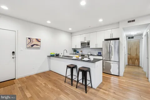 a kitchen with a refrigerator a stove a sink and white cabinets with wooden floor