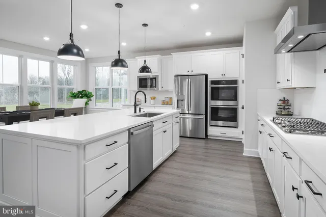a large white kitchen with lots of counter space and wooden floor