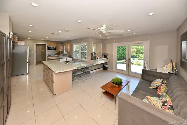 a living room with stainless steel appliances furniture a rug and a view of kitchen