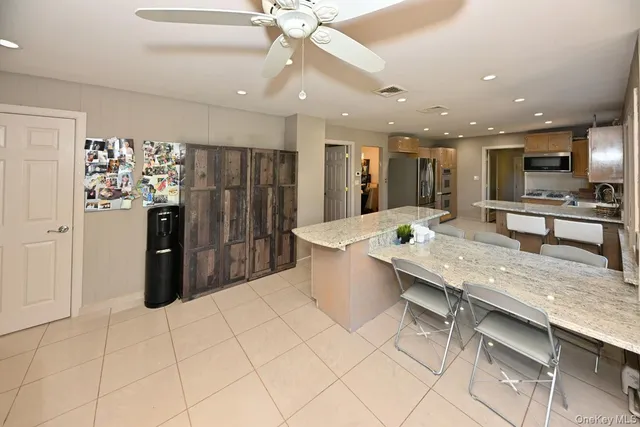 a kitchen with stainless steel appliances kitchen island granite countertop a refrigerator oven a sink dishwasher and white cabinets with wooden floor