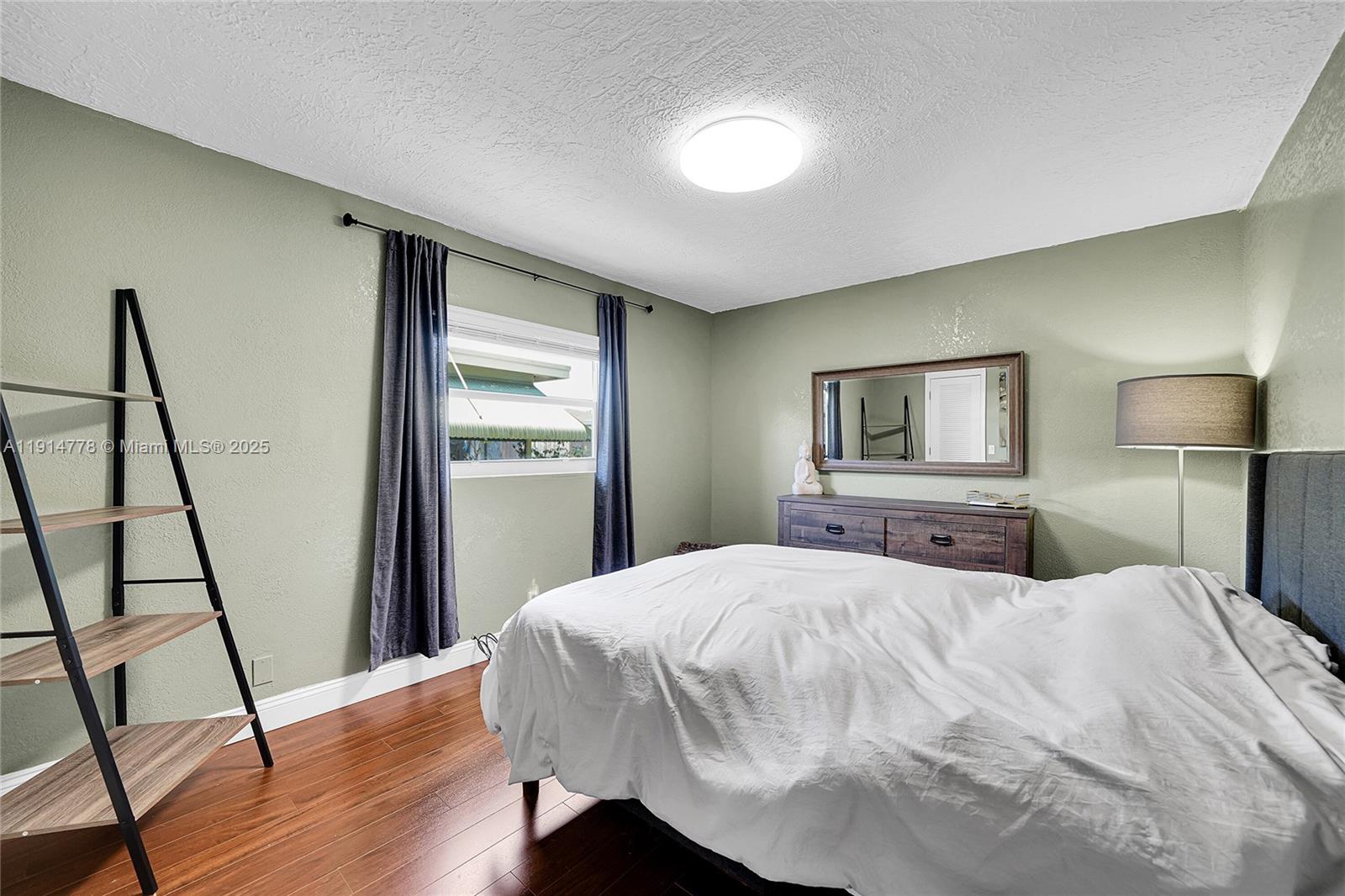 6001 Northwest 66th Terrace Tamarac, FL 33321 - Photo 23 of 30 a bedroom with a bed and a flat tv screen on a dresser