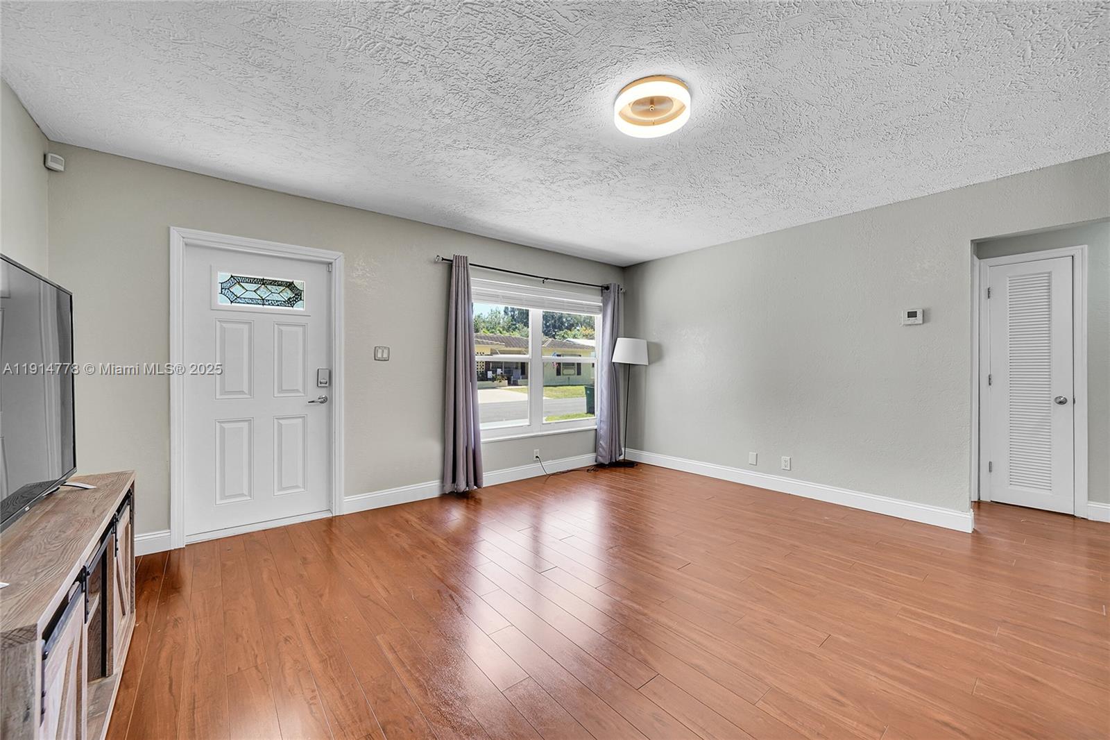 6001 Northwest 66th Terrace Tamarac, FL 33321 - Photo 3 of 30 a view of an empty room with wooden floor and a window