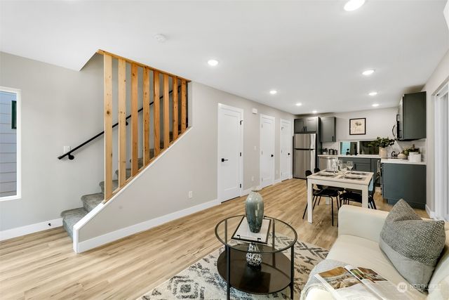 a living room with furniture and kitchen view with wooden floor