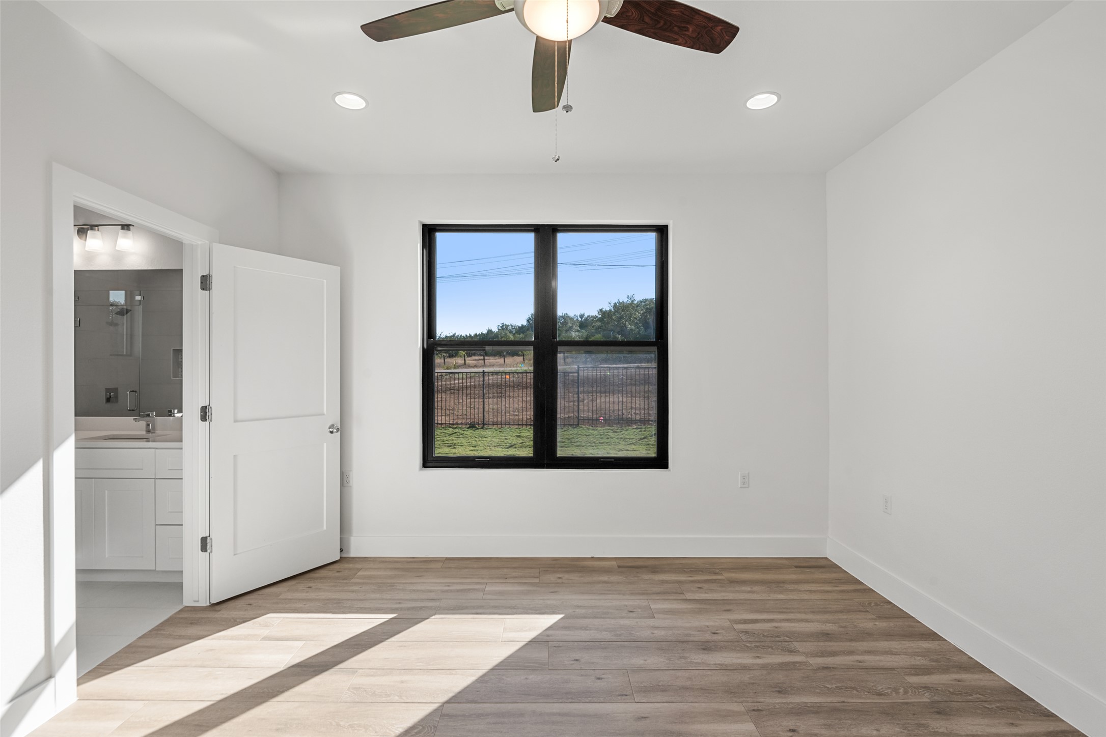 711 Paleface Ranch Road, Unit 3 Spicewood, TX 78669 - Photo 13 of 32 an empty room with wooden floor cabinet and windows