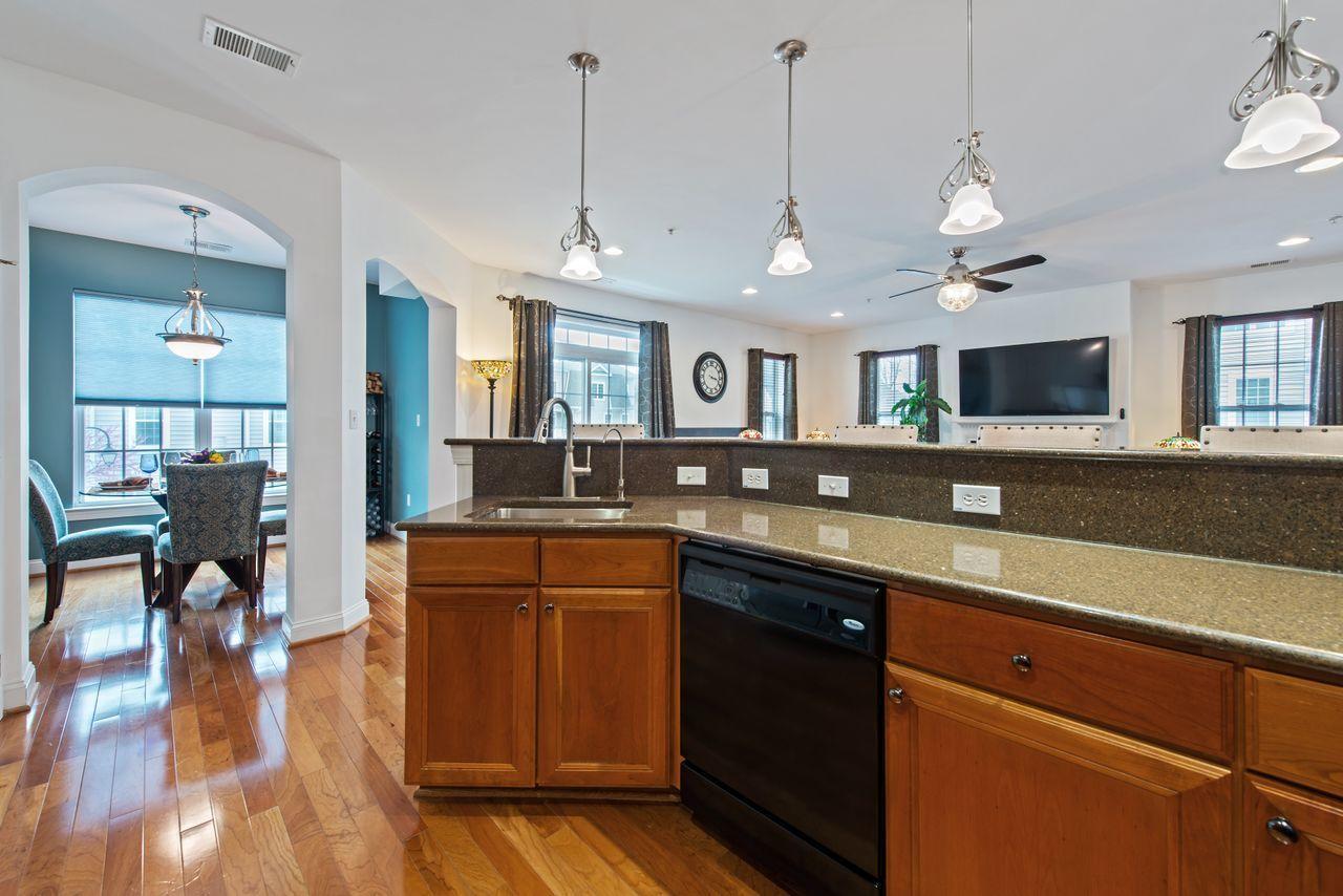 501 Abby Road Middletown, NJ 07748 - Photo 11 of 36 a open kitchen with stainless steel appliances granite countertop a stove a sink dishwasher a dining table and chairs with wooden floor