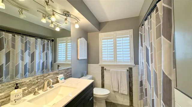 a bathroom with a granite countertop sink a toilet and a mirror