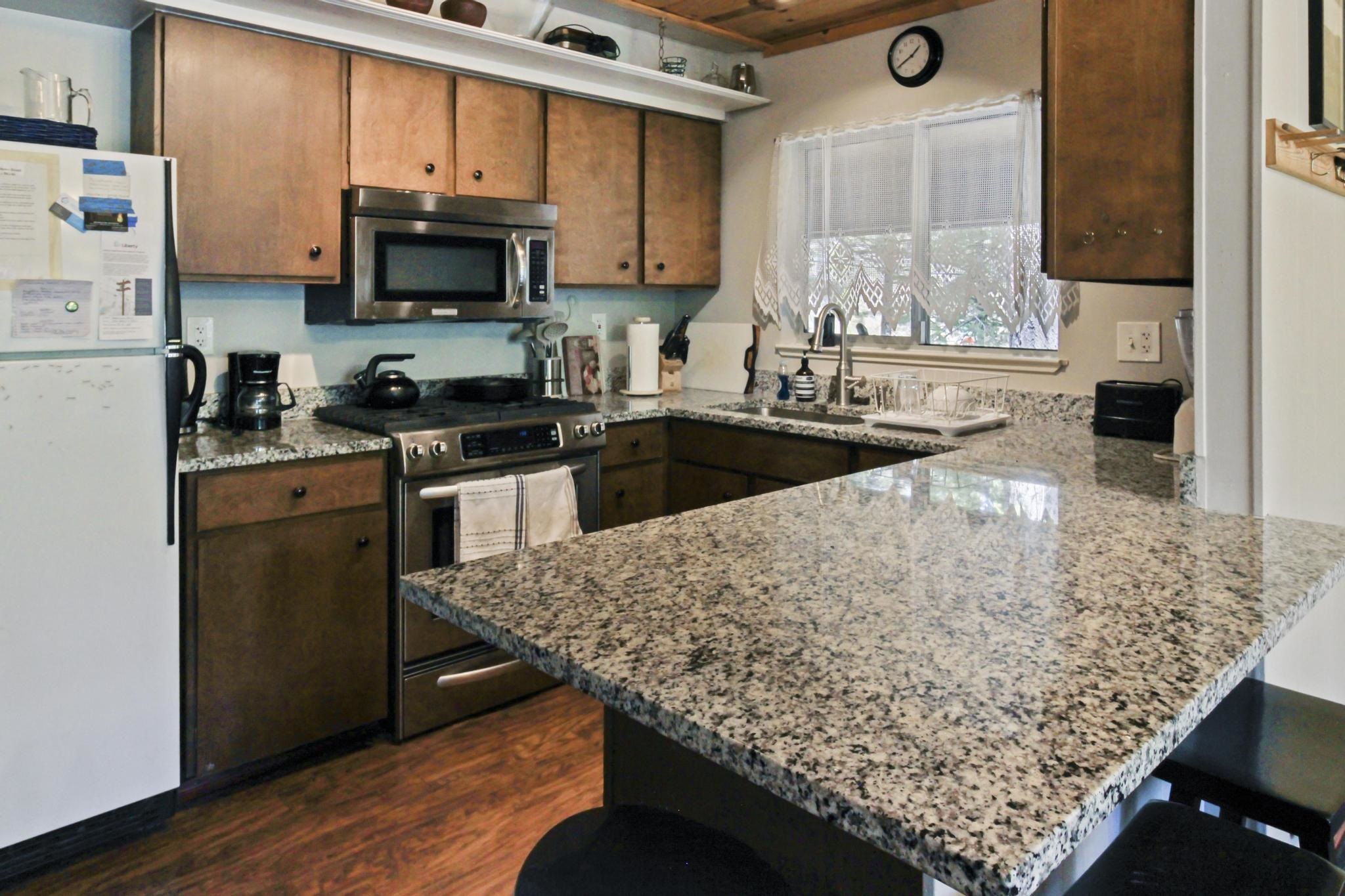 1503 Alpine Meadows Road Alpine Meadows, CA 96146 - Photo 8 of 28 a kitchen with stainless steel appliances kitchen island granite countertop wooden cabinets a stove top oven a sink and dishwasher with wooden floor