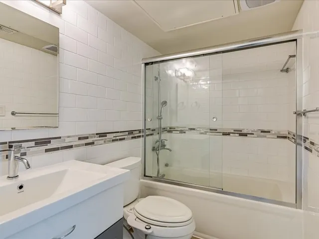a bathroom with a sink mirror shower and toilet