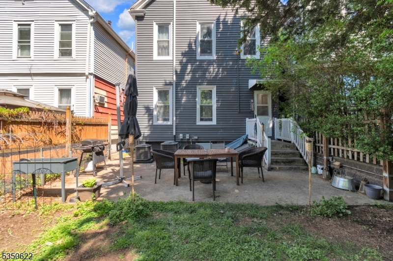 26 Grand Street, Unit 1 Garfield, NJ 07026 - Photo 7 of 9 a view of a patio with table and chairs and potted plants and large tree