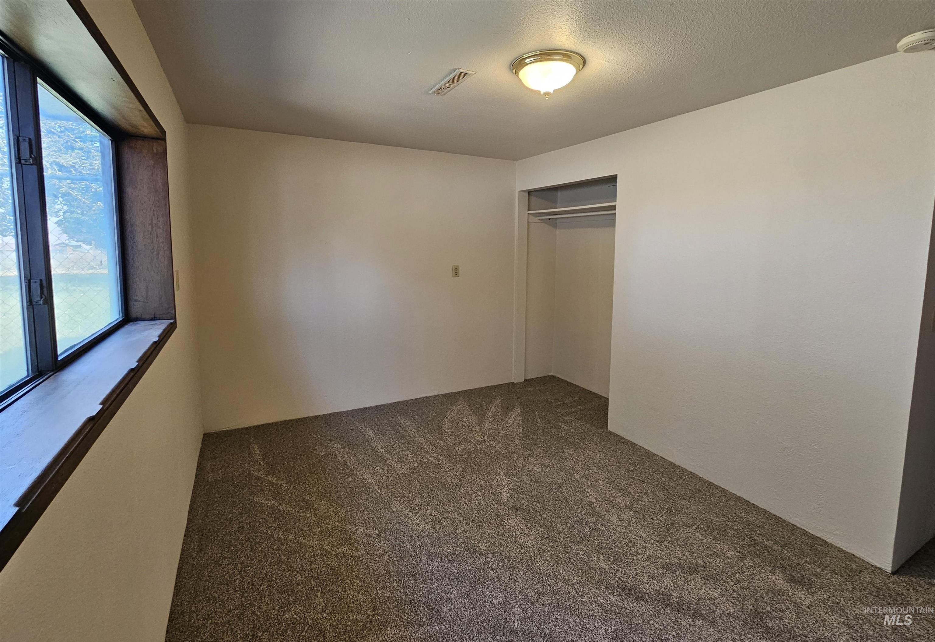 1825 Cedar Avenue Lewiston, ID 83501 - Photo 25 of 39 Unfurnished bedroom featuring dark carpet, a closet, and a textured ceiling