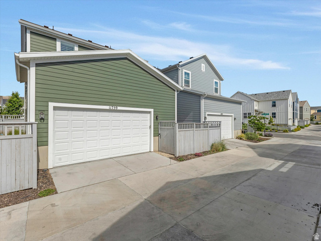 11759 South Watercourse Road South Jordan, UT 84009 - Photo 24 of 33 Property exterior featuring a two-car garage with a white paneled door, green horizontal siding, and a concrete driveway