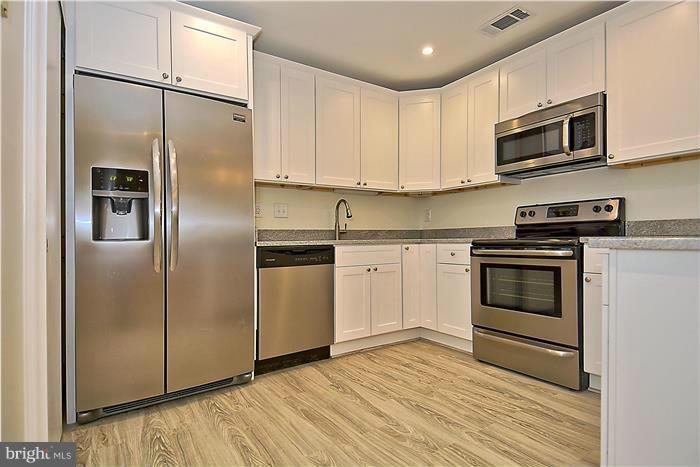 10706 Kings Riding Way, Unit T218 Rockville, MD 20852 - Photo 7 of 17 a kitchen with granite countertop a refrigerator stove and microwave