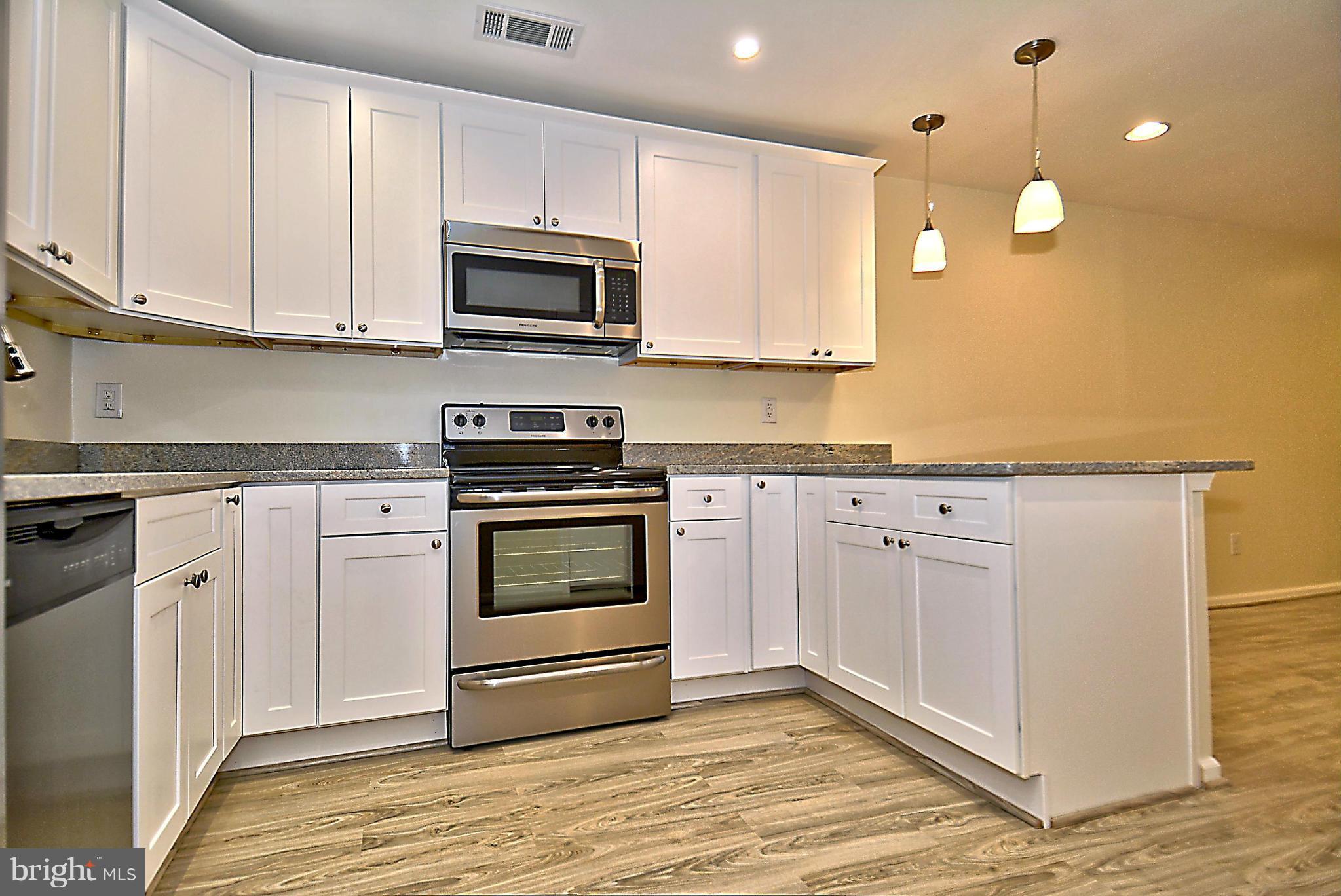 10706 Kings Riding Way, Unit T218 Rockville, MD 20852 - Photo 9 of 17 a kitchen with granite countertop white cabinets stainless steel appliances and a counter space