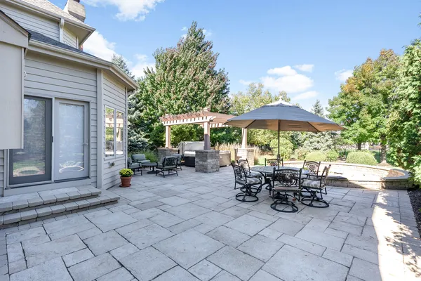 a view of the patio with chairs and table under an umbrella