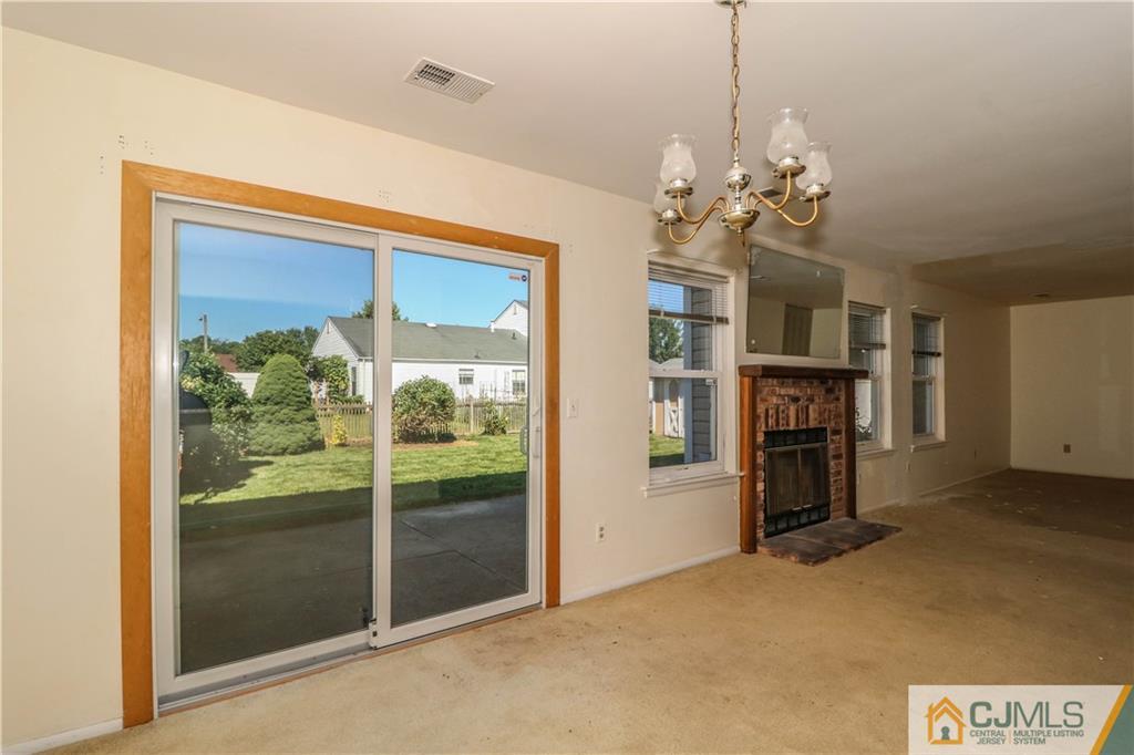 48 Woodbrook Road Edison, NJ 08820 - Photo 7 of 22 a view of a livingroom with a fireplace a chandelier and windows