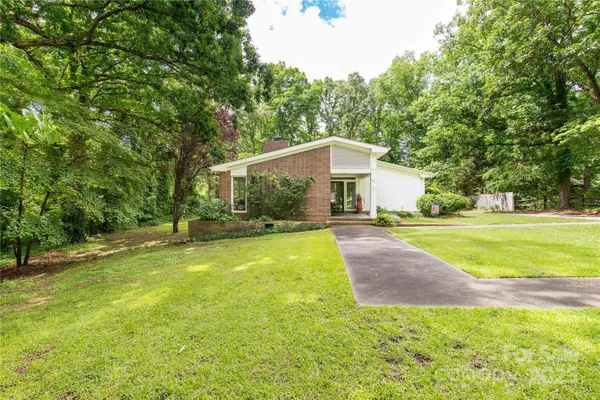 a view of a house with a yard and palm trees