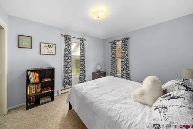 a bedroom with a bed a painting on the wall and a window