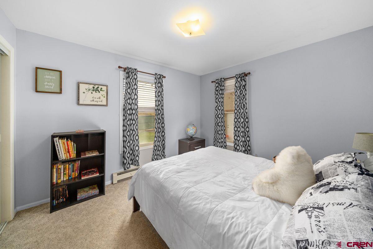 66460 Ogden Road Montrose, CO 81401 - Photo 21 of 40 a bedroom with a bed a painting on the wall and a window